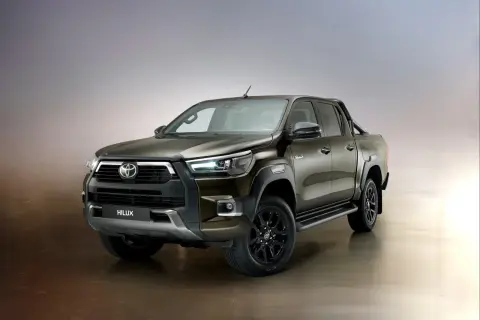 Brązowy Toyota Hilux Invincible z czarnymi felgami i relingami, gotowy na każde wyzwanie.