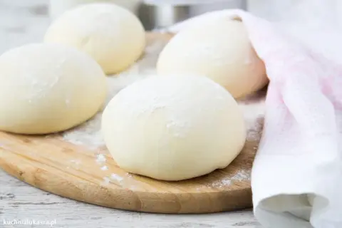 Kulki ciasta na pizzę, posypane mąką, leżą na desce. Zastanawiasz się, czy można mrozić ciasto na pizzę? Tak, można!