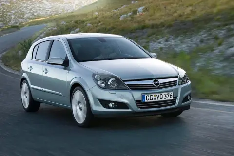 Srebrny Opel Astra GTC z kierowcą za kierownicą pokonuje zakręt na górskiej drodze.