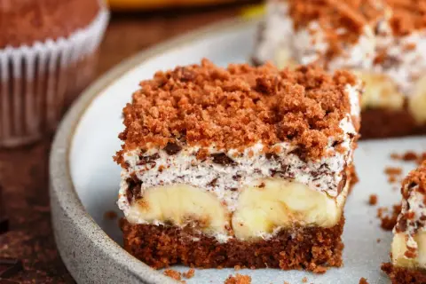 Pyszny kopiec kreta z bananami, kremem i czekoladą, posypany kruszonką.