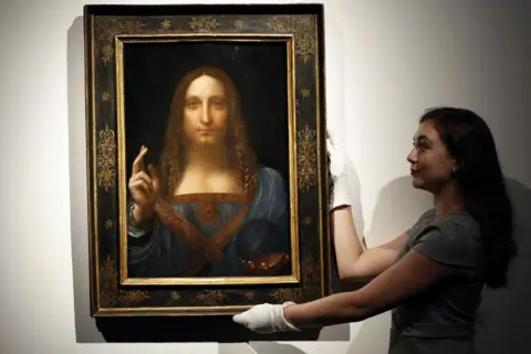 Frau mit weißen Handschuhen präsentiert das Gemälde "Salvator Mundi" von Leonardo da Vinci.