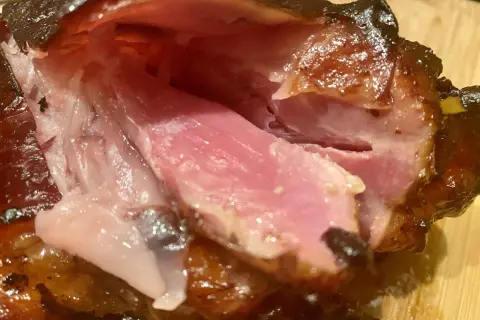 Gros plan sur des kakos de porc juteux et caramélisés, la chair rose tendre contrastant avec la peau croustillante.
