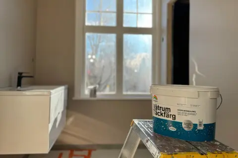 En hink med Beckers Våtrum Täckfärg står på en stege i ett badrum under renovering. Följ regler för att måla i badrum.