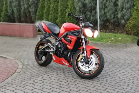 Czerwony motocykl Triumph Street Triple 675 na brukowanym podjeździe.