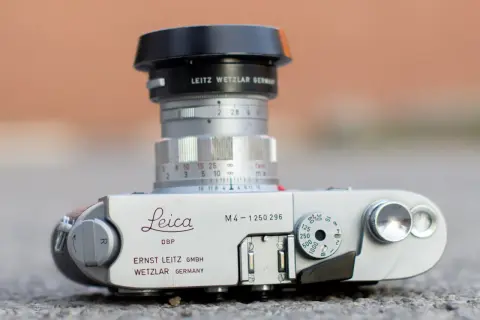 A Leica M4 camera with a Leitz Wetzlar lens. The camera body shows "Leica M4" and "Ernst Leitz GmbH Wetzlar Germany." The lens has aperture markings and a focus ring. The framelines are not visible in this shot.