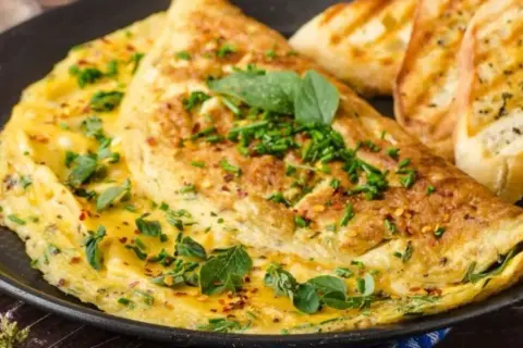 Puszysty omlet bez mąki, posypany szczypiorkiem i płatkami chili, podany z grzankami czosnkowymi. Idealne śniadanie.