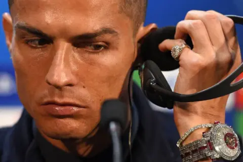 Cristiano Ronaldo luce un reloj de 2 millones de dólares, incrustado de diamantes y rubíes, mientras se prepara para una entrevista.