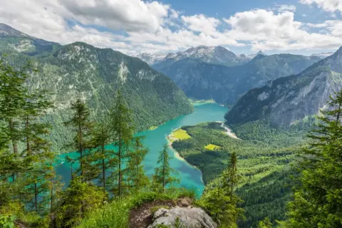 Türkisblaue Bergseenlandschaft mit bewaldeten Hängen und Gipfeln. Ein atemberaubender Ausblick in einem wilden Nationalpark.