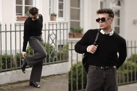 Mann in schwarzem Pullover, weißem Hemd und dunkler Hose, bereit für ein Techno-Festival. Coole Sonnenbrille und Stiefel runden den Look ab.