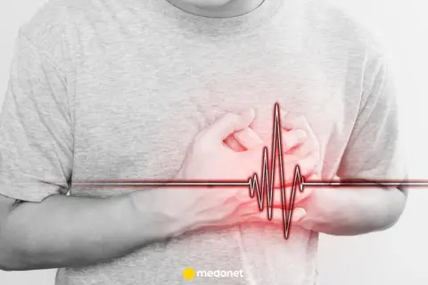 Osoba trzyma się za serce, na którym widnieje wykres EKG. Może to symbolizować problemy z sercem, jak np. arytmia, lub po prostu stres.