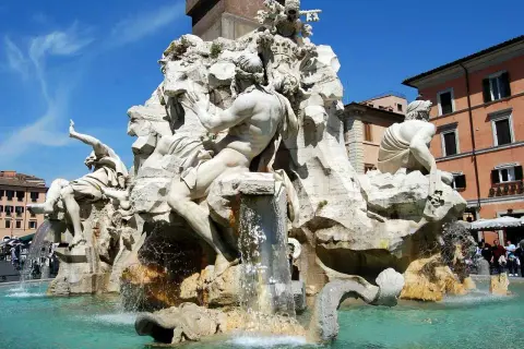 La Fontana dei Quattro Fiumi di Bernini, con le sue maestose statue che rappresentano i fiumi del mondo, zampilla sotto il cielo azzurro di Roma.