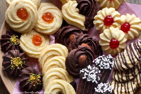 Variazioni di frolla montata: biscotti al cacao con mandorle e pistacchi, frollini con marmellata d'arancia e ciliegia, e decorati con cioccolato.