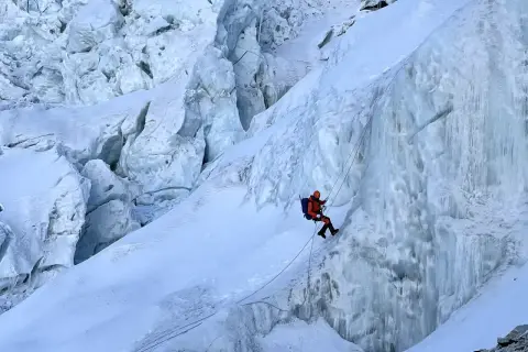 Bergsteiger seilt sich im Khumbu Icefall ab, umgeben von zerklüftetem Eis und tiefen Gletscherspalten.
