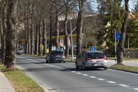 Dwa samochody z literą "L" na dachu, przygotowujące się do egzaminu praktycznego na prawo jazdy. Zastanawiasz się, ile kosztuje egzamin praktyczny na prawo jazdy?