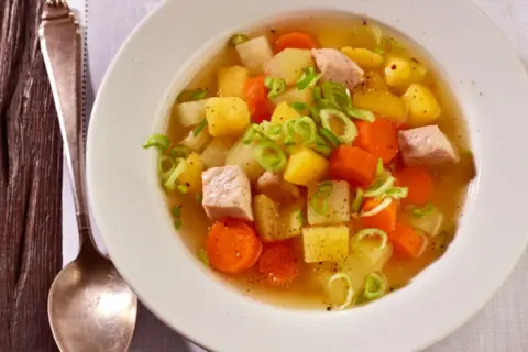 Herzhafter Kohlrabi-Eintopf mit Fleischwürfeln, Kartoffeln und Karotten, garniert mit Frühlingszwiebeln.