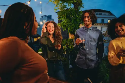 Vänner samlas på en takfest i Berlin, med ljusslingor och stadens silhuett i bakgrunden. En kväll fylld av skratt och goda drinkar, som en liten bit av fakta om Berlin.