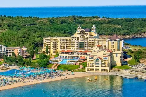 Duni Royal Pelican: luksusowy hotel z basenami i plażą nad morzem, otoczony zielenią.
