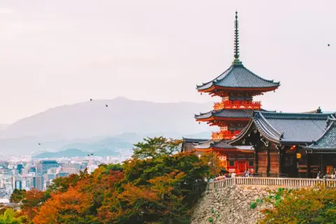 Widok na pagody i tradycyjną architekturę w Kioto, które kiedyś było stolicą Japonii. W tle rozciąga się miejski krajobraz.