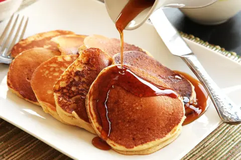 Pancakes dorati, preparati con bicarbonato al posto del lievito, vengono irrorati da uno sciroppo ambrato.