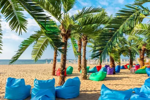Kolorowe pufy i palmy na plaży w Bułgarii. Złote Piaski oferują mnóstwo atrakcji dla każdego.