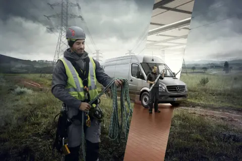 En tekniker med rep förbereder sig för arbete vid elledningar. En annan tekniker putsar vindrutan på en Mercedes-skåpbil i en verkstad.