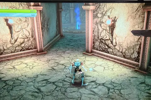 Postać w zbroi w grze medievil 2 remake przemierza kamienny korytarz z pochodniami i niebieskim płomieniem w oddali.