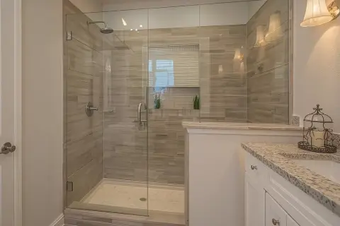 A modern bathroom featuring a spacious glass-enclosed shower with wood-look tile walls, a testament to a successful DIY shower tile installation.
