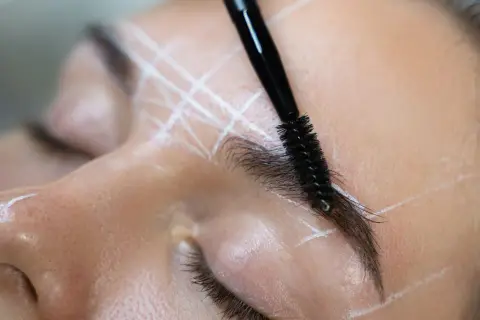 Zbliżenie na brwi z zaznaczonymi liniami i szczoteczką do ich modelowania.