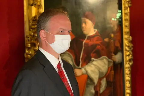 Hombre con mascarilla frente a un retrato del papa León X.
