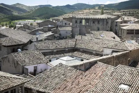 Tejado de un pueblo con colinas al fondo. Se vislumbran las torres del puente de San Valero.
