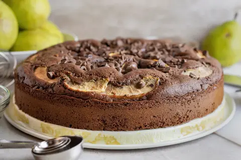 Torta pere e cioccolato, soffice e golosa, con tante gocce di cioccolato e fette di pera che spuntano dalla superficie.