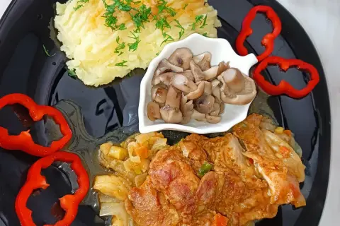 Mięso z udka kurczaka bez kości w sosie, podane z puree ziemniaczanym, marynowanymi grzybami i papryką. Idealne na obiad.