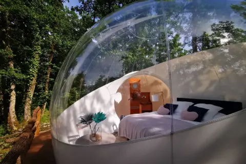Une bulle transparente au cœur de la nature pour dormir dans une bulle Occitanie. Lit douillet, table et fleurs pour un séjour unique.