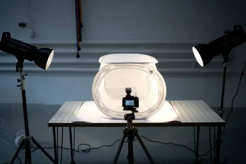 Studio do fotografii produktowej z aparatem na statywie, dyfuzorem i dwoma lampami tworzącymi światło kontrowe.