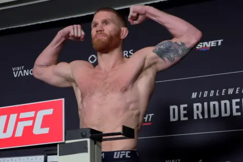 Matt Frevola, med skägg och tatueringar, poserar muskulöst på UFC-vågen.