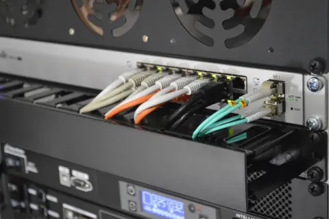 Światłowody jednomodowe i wielomodowe: zielone kable światłowodowe podłączone do SFP. Różnice widać po grubości i kolorze.
