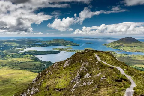 Sentier de randonnée Connemara, vue panoramique sur les lacs et les îles sous un ciel nuageux.