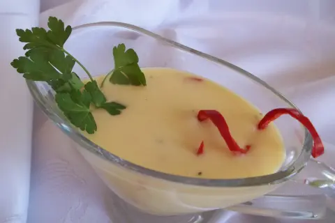 Kremowy sos cytrynowy do ryby, ozdobiony natką pietruszki i papryczką chili.