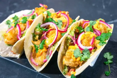 Fisktacos recept: Krispiga fiskbitar, krämig sås, rödlök och koriander i mjuka tortillabröd. En fest för smaklökarna!