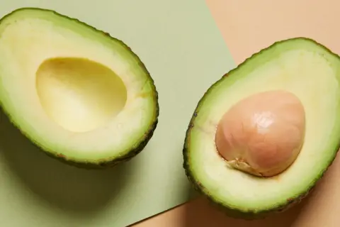 Deux moitiés d'avocat, l'une sans noyau, l'autre avec son noyau. Un aliment sain, mais attention à la prise de poids si consommé en excès.