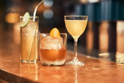 Tre läckra drinkar på en bardisk, redo att avnjutas. En med lime, en med apelsin och en i martiniglas. Perfekt för goda drinkar!