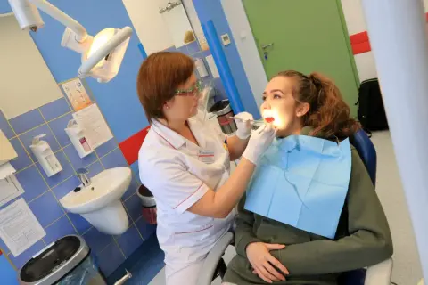 Dentystka bada zęby młodej pacjentki w gabinecie stomatologicznym.
