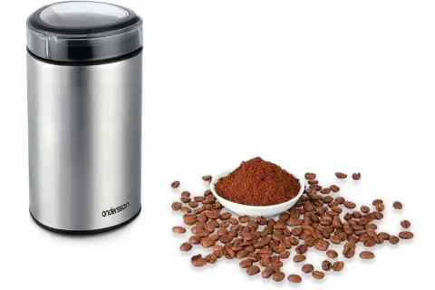 En kaffekvarn i metall bredvid en skål med kaffepulver och bönor. Perfekt för att lära sig hur brygger man kaffe.