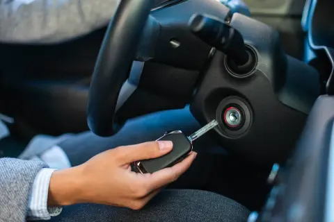 Ręka trzyma kluczyk do stacyjki, próbując uruchomić auto. Wygląda na to, że jest problem z immobilizerem.
