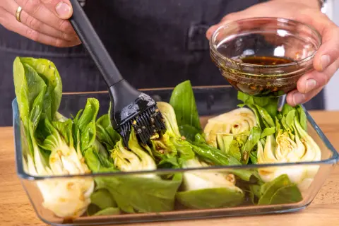 Marinade wird mit einem Pinsel auf halbierten Pak Choi aufgetragen, bereit zum **Pak Choi grillen**.