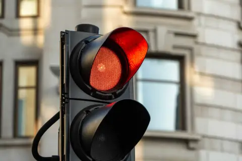 Un feu rouge clignote, signalant un danger. Le radar est prêt à flasher une fois.