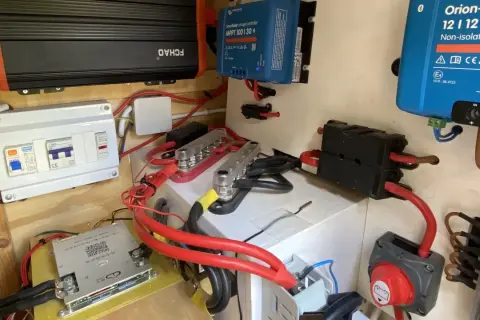 Sistema eléctrico con varios componentes, incluyendo un inversor, regulador solar y disyuntores. El grosor del cable eléctrico es notable en las conexiones principales.