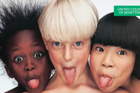 Tre bambini di etnie diverse, in una delle fotografie famose a colori di Oliviero Toscani, fanno la linguaccia.