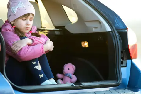 Traurige Kinder im Kofferraum, nur ein Teddybär als Gesellschaft.