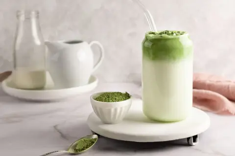 Idealny matcha latte przepis: zielony proszek, mleko i gotowy napój w szklance.